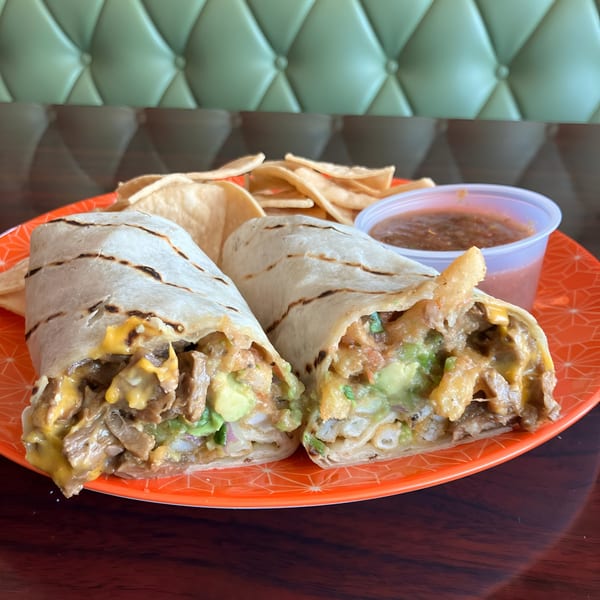 Two vegan burritos with fries, guacamole, and cheese, served with tortilla chips and salsa.