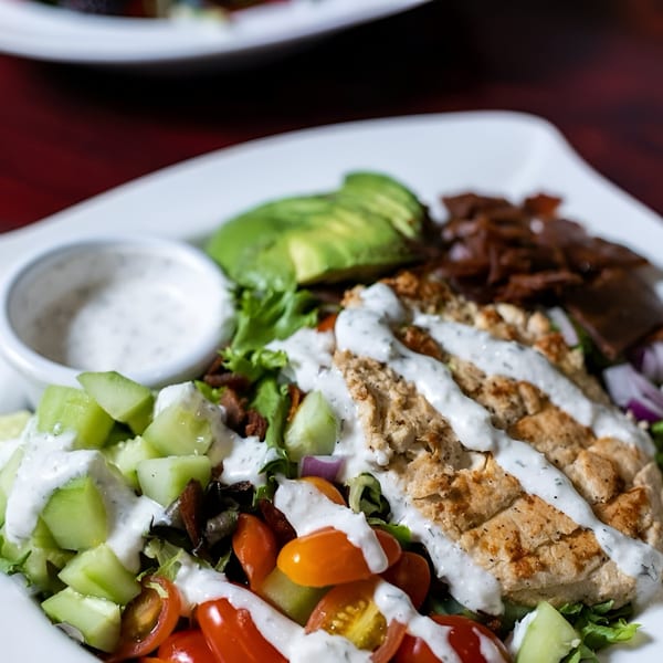 Vegan Cobb salad with plant-based chicken, avocado, tomatoes, cucumbers, and ranch dressing.